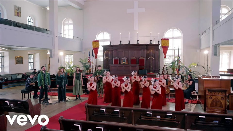 Performers in yellow and blue gowns on a church stage.